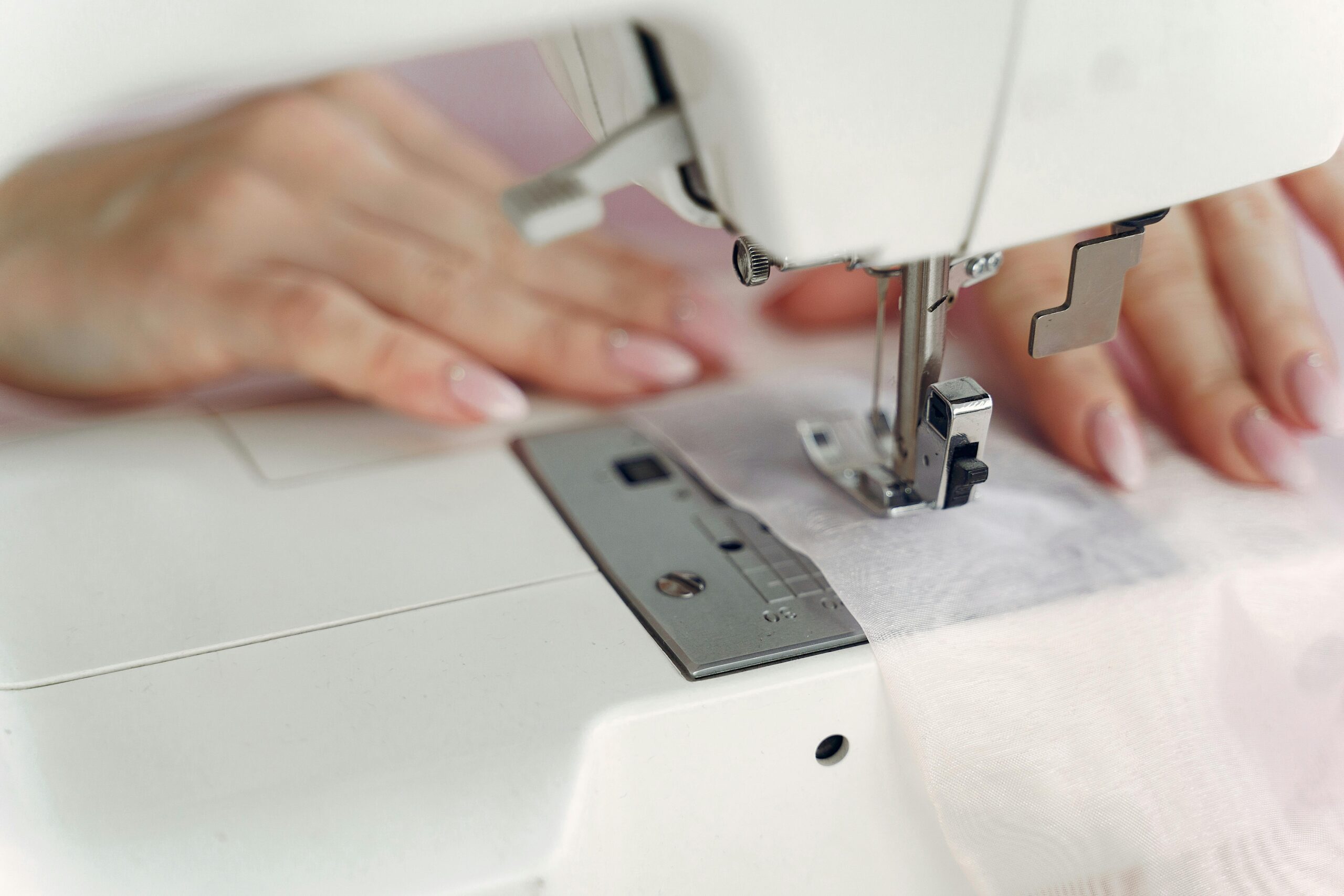A seamstress skillfully using a sewing machine to stitch fabric indoors.